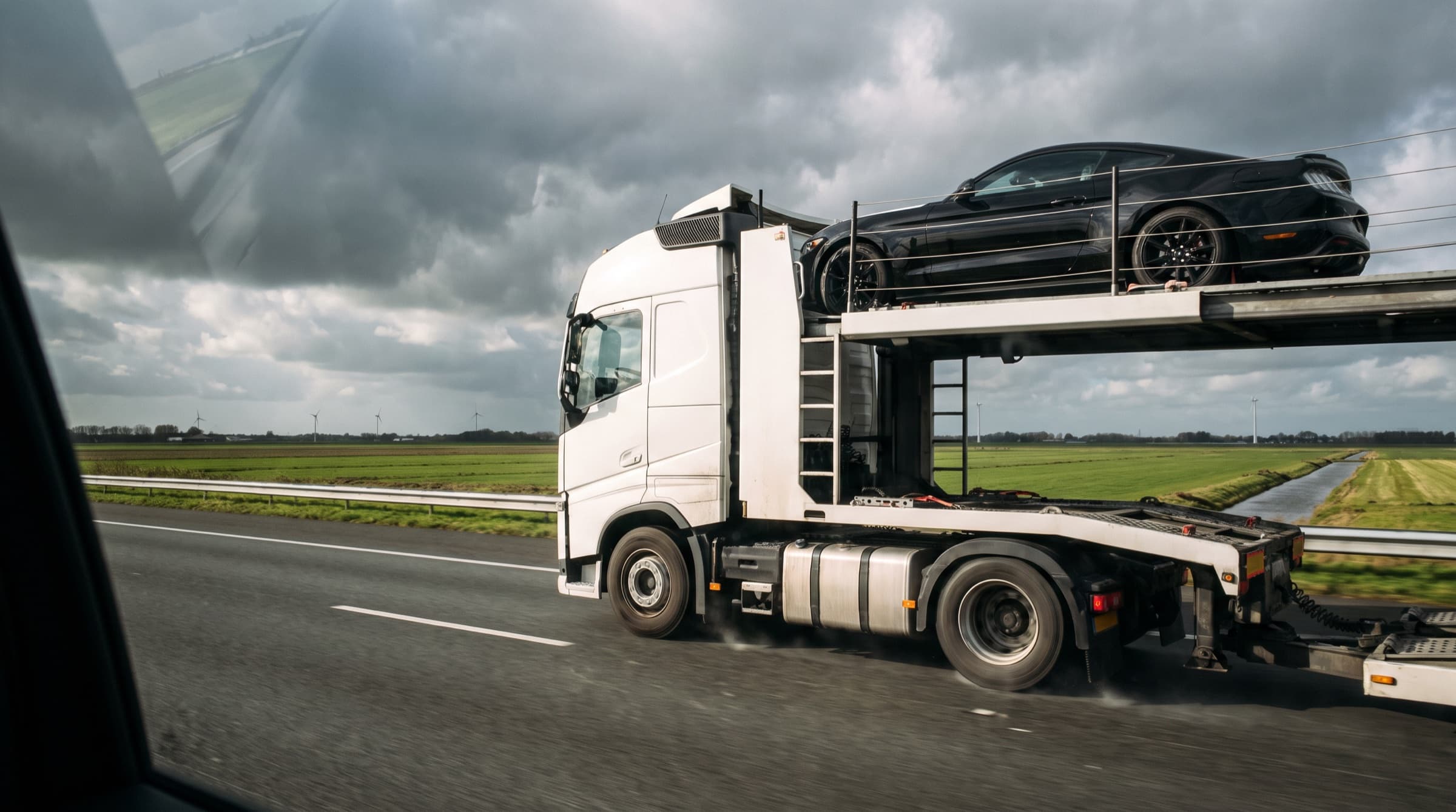 Vrachtwagen-autotransporter op de snelweg door de polder