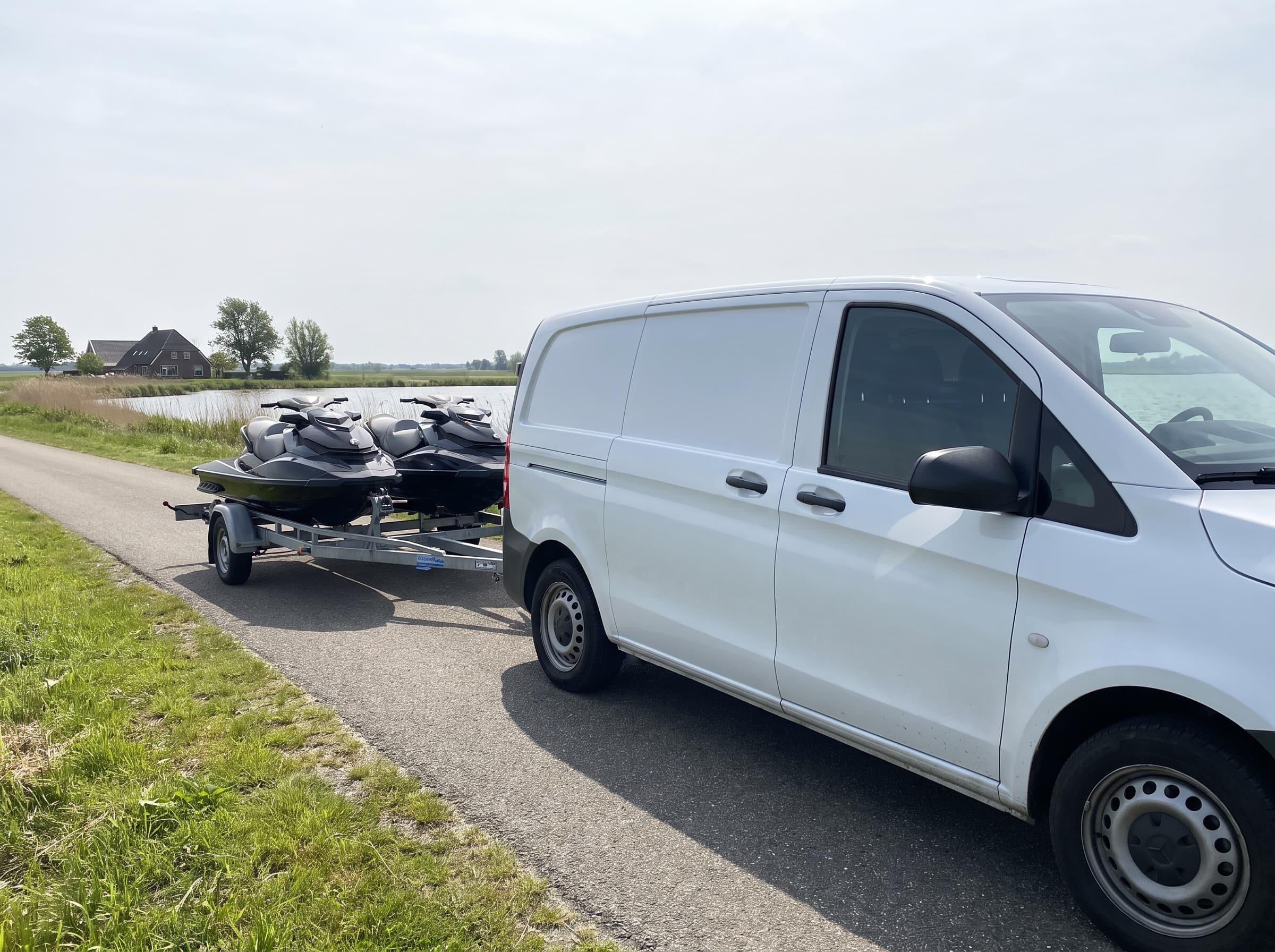 Twee jetski's op een trailer achter een bestelbus